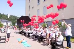Nach einem Sitztanz lassen Bewohner und Mitarbeiter des DRK-Seniorenzentrums Ballons fliegen.
