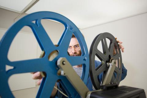 James Edmonds fädelt vor dem Beginn des Kurzfilmabends mit seinen Arbeiten in der Kunsthalle einen Film in den 8-mm-Projektor ein. Foto: hbz/Judith Wallerius