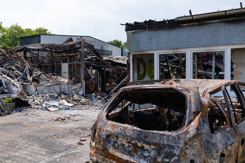 Trümmer des Gebäudes und ausgebrannte Fahrzeuge prägen das Bild auf dem Gelände, wo früher die Lagerhalle stand.