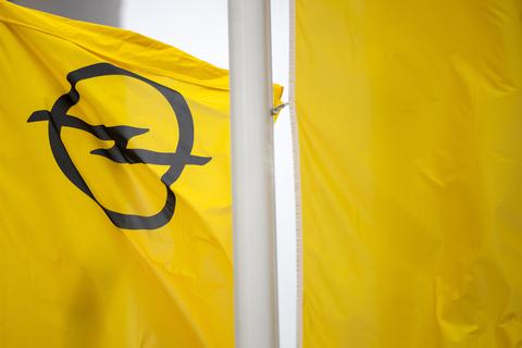 Flaggen mit dem Opel-Logo wehen vor einem Opelwerk. Foto: dpa