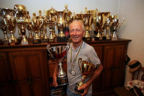 Die Trophäen auf dem Schrank bilden nur einen Teil der Erfolge einer 70-jährigen Radsportler-Laufbahn ab. In den Händen hält der zehnfache Senioren-Weltmeister Bruno Podesta die Pokale für seine jüngsten Siege. Foto: Ulrich von Mengden