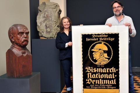 Sabine Markowski und Matthias Schmandt zeigen im Museum am Strom ein erhaltenes Plakat, mit dem deutschlandweit für Spenden geworben wurde, um das Bismarck-Denkmal auf der Elisenhöhe realisieren zu können. Foto: Thomas Schmidt