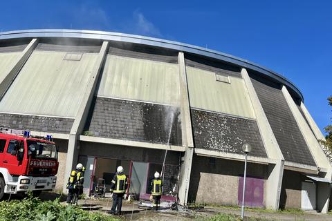 Leichter Rauch steigt an der Rundsporthalle in Nierstein auf, während die Feuerwehr löscht. 
