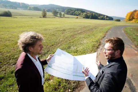 Bauamtsleiter Norbert Schmidt (links) und Bürgermeister Christoph Felkl schauen oberhalb von Oberdieten in die Pläne zum Hochwasserschutz. Auf dem Feld im Hintergrund sollen an der Diete so genannte Vorlandwälle gebaut werden, in die sich der Bach bei Hochwasser ausbreiten kann – das soll größere Wassermengen aus dem Dorf heraushalten.  Foto: Adel