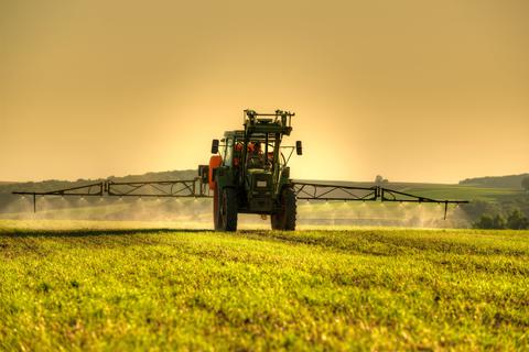 Ein Traktor verteilt Pestizide auf einem Acker. 