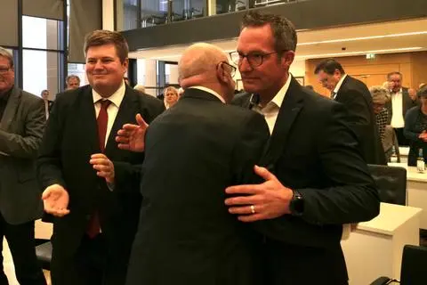 Der neue Landrat Carsten Braun (CDU) und der scheidende Landrat Wolfgang Schuster (SPD) umarmen sich bei der Verabschiedung Schusters in Kreistag. CDU-Kreisparteichef Johannes Volkmann (links) hat zuvor mit SPD-Kreisparteichef Schuster die neue Koalition im Kreis geschmiedet. 
