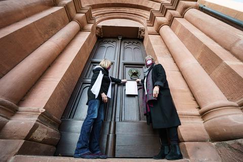 Andrea Keber (l.) und Beate Berdel-Mantz von der Reforminitiative Maria 2.0 Nieder-Olm schlagen ihre Thesen an die Kirchentüre des Mainzer Doms an.  Foto: dpa