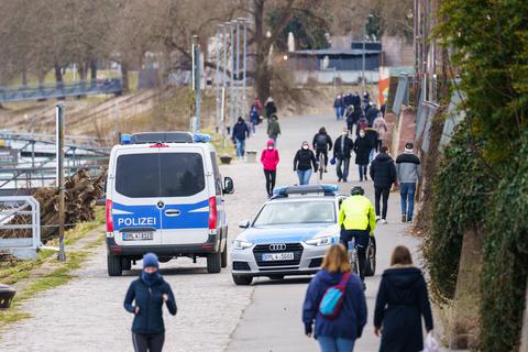 Zwei Polizeiautos fahren am Mainzer Rheinufer Streife und kontrollieren dabei die Einhaltung der Maskenpflicht. Foto: dpa