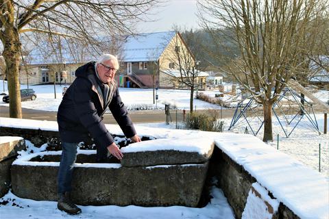 Gerald Jaksche erklärt den älteren der beiden Stein-Särge, die an der Friedhofsmauer in Rehbach stehen. Foto: Manfred Giebenhain