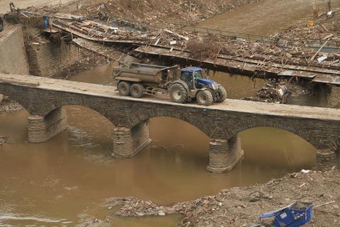 Kreuzberg: Ein Traktor fährt über eine vom Hochwasser zerstörte Ahrbrücke. Foto: dpa