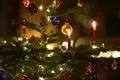 Kerzen brennen an einem geschmückten Christbaum.