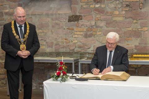 Bundespräsident Frank-Walter Steinmeier trägt sich ins Goldene Buch der Stadt Worms ein, Oberbürgermeister Adolf Kessel sieht es mit Freude.