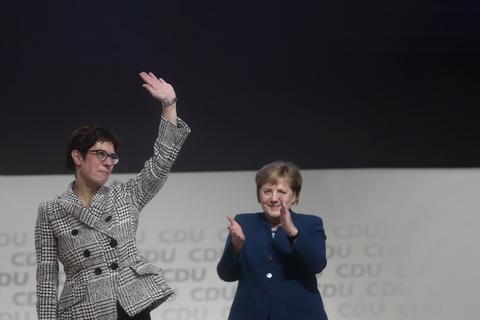 Die neue CDU-Vorsitzende Annegret Kramp-Karrenbauer (l) winkt auf dem CDU-Bundesparteitag zu den Delegierten. Rechts im Hintergrund steht ihre Vorgängerin und Bundeskanzlerin Angela Merkel. Foto: Michael Kappeler/dpa