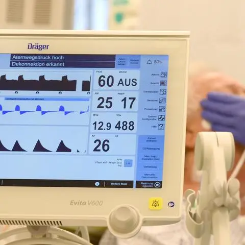 Auf der Covid-Station einer Klinik versorgt ein Intensivpfleger einen Patienten, der an ein Beatmungsgerät angeschlossen ist.