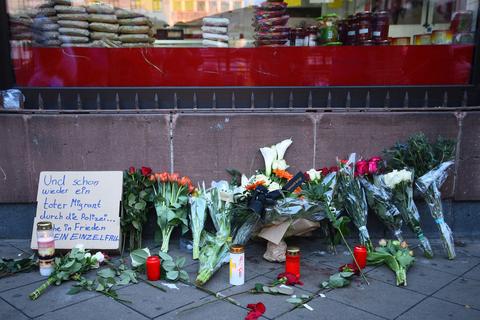 Blumen liegen an dem Ort, an dem am Montag ein Mann nach einer Polizeikontrolle gestorben ist. Daneben steht ein Pappschild mit der Aufschrift «Und schon wieder ein toter Migrant durch die Polizei...». Die Leiche des Mannes wurde für weitere Untersuchungen beschlagnahmt, wie die Staatsanwaltschaft Mannheim und das Landeskriminalamt (LKA) Baden-Württemberg in Stuttgart mitteilten.  Foto: dpa
