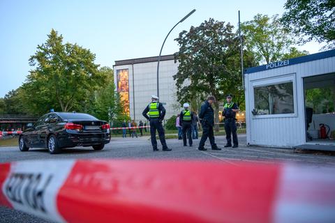 Mehrere Polizeibeamte und Zivilisten stehen nach dem Angriff im abgesperrten Bereich vor der Synagoge. Foto: dpa