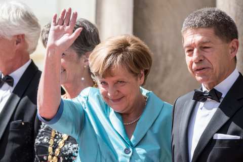 Bundeskanzlerin Angela Merkel winkt neben Ehemann Joachim Sauer vor der Eröffnung der 104. Bayreuther Festspiele. Foto: dpa