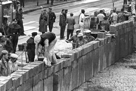 18.08.1961, DDR, Berlin: Unter der Aufsicht von bewaffneten Volkspolizisten errichtet eine Ostberliner Maurerkolonne an der sowjetisch-amerikanischen Sektorengenze am Potsdamer Platz eine Mauer.  Foto: UPI/UPI_dpa/dpa