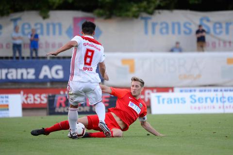 Mit Kapitäns-Binde und mit vollem Einsatz: Wormatias verletzter Mittelfeldspieler Eric Lickert (rotes Trikot) vor seiner schlimmen Verletzung in einem Spiel gegen die TSG Pfeddersheim. Archivfoto: BilderKartell / Martin H Hartmann 